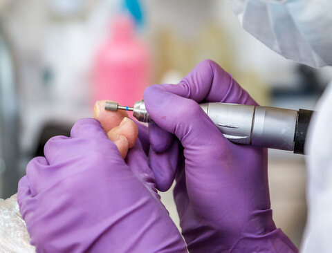 Pedicure behandeling Pedicure behandelt de voeten van haar klant met een frees